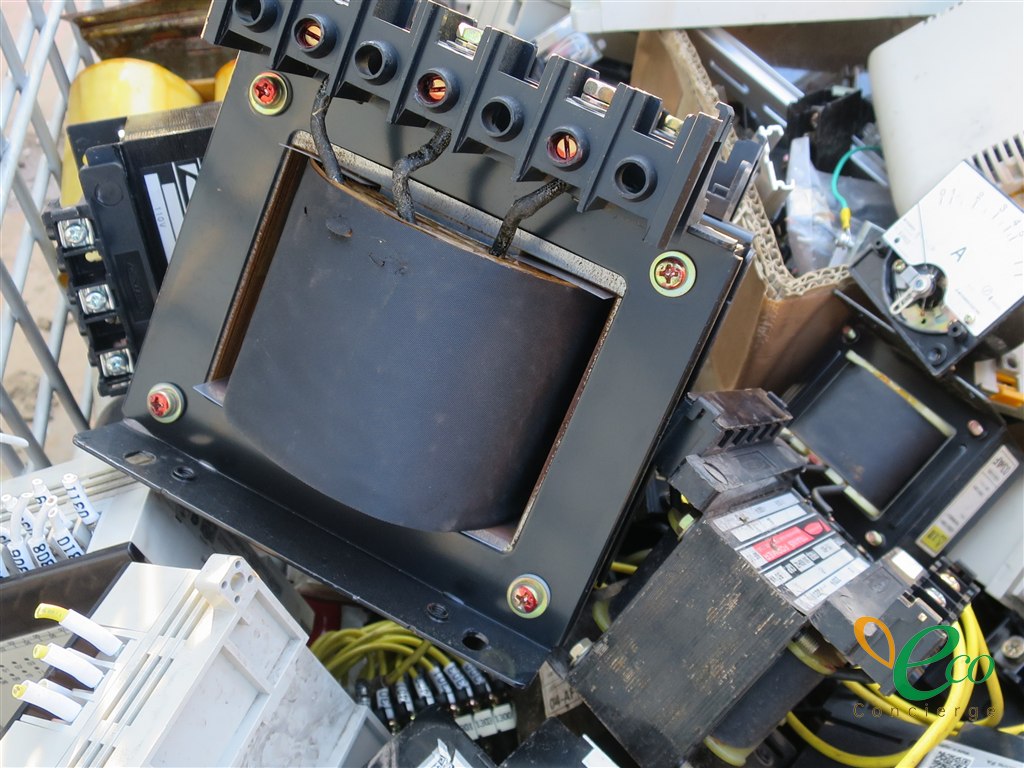 金属カゴの中にある小型トランス1台を近くから撮影した様子。黒いブラケットに固定されたコイル部分が見える
