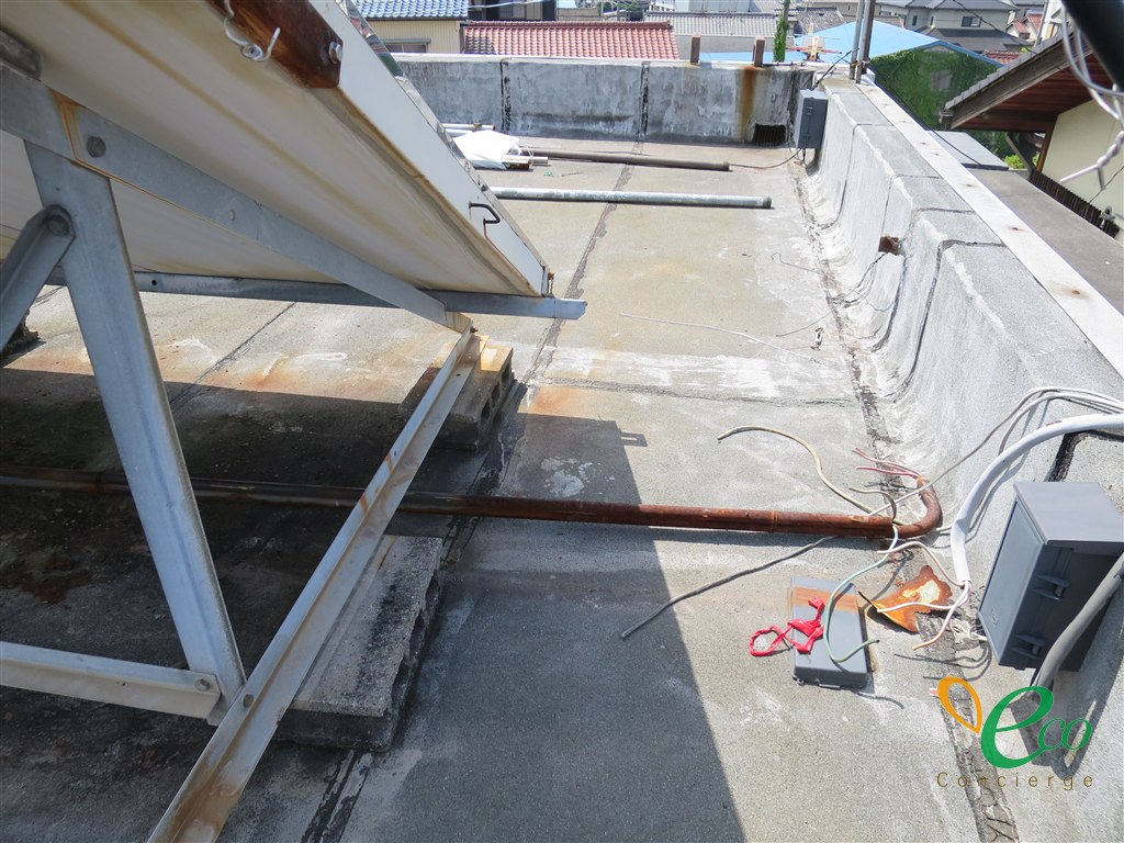 太陽熱温水器の架台の下を通る配管と、屋上に残る電気配線