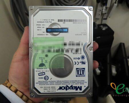 取り外したハードディスクを手に持って、ラベル面を見せている様子。シリアル番号の部分はモザイク処理をしています